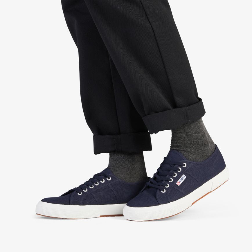 navy blue canvas sneakers with white rubber outer sole modelled with grey socks and black slack pants